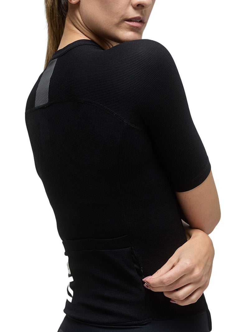 Side view of a woman in a black Givelo Modern Classic jersey, showing the comfortable fit and the textured fabric designed to provide functional benefits while cycling.
