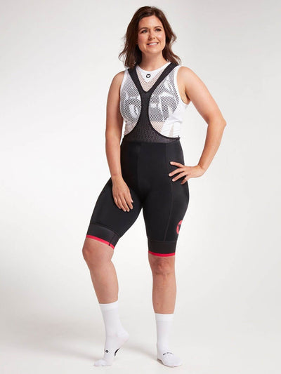 Woman wearing Black Sheep Cycling women's bib shorts in black and pink. Durable and comfortable with CorePower compression fabric.