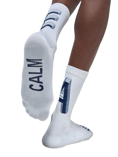 The back view of white Givelo G-Socks from the Chaos line is shown, with a striking black design accentuating the leg's muscular contours and the "Chaos" branding visible below the cuff.