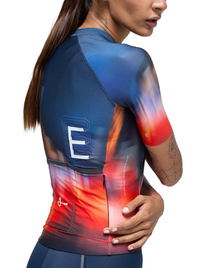 Close-up of the Givelo Essentials Chaos cycling jersey with vibrant red to blue gradient and text detail.