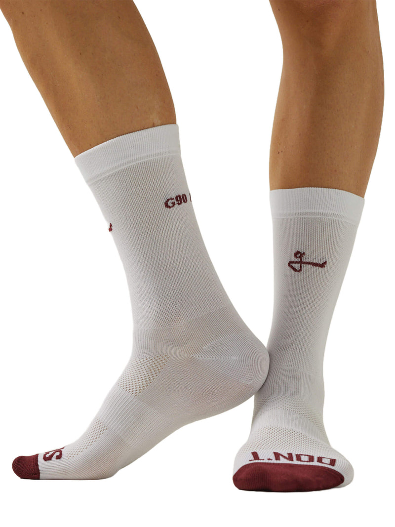 Image showing a front view of a pair of feet wearing Givelo G-Socks in white with red accents. The socks have distinct cushioning on the sole and a ribbed texture for grip, along with the brand&