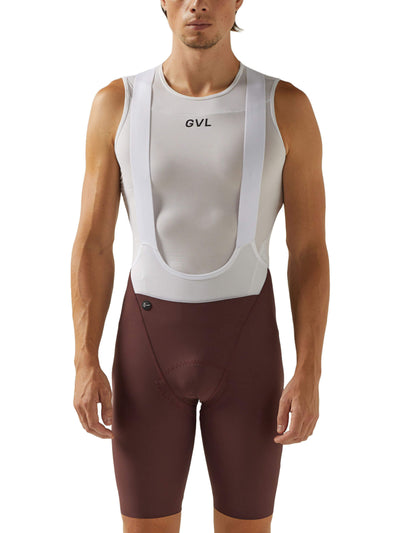 Front view of a man in merlot-colored Givelo HD Pro Bib Shorts paired with a white and grey cycling vest. The shorts boast a precision fit with a seamless construction and a central logo, designed for long-distance cycling.