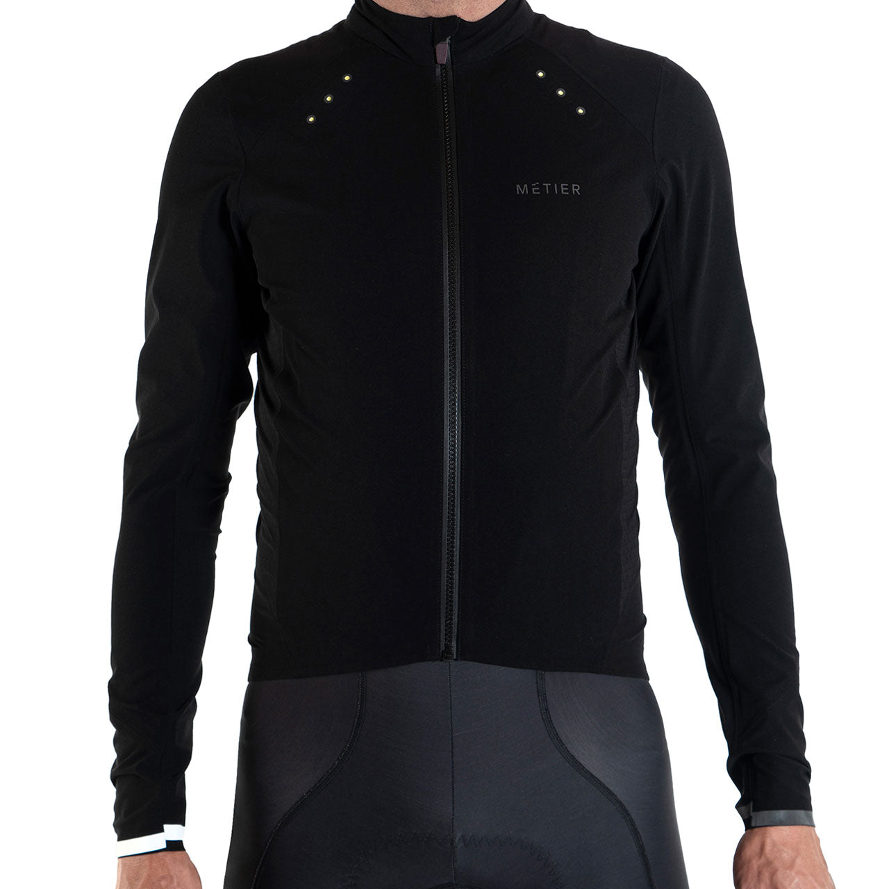 Front view of black Metier Beacon Jacket with integrated LED lights on shoulders and zipper closure, worn by cyclist