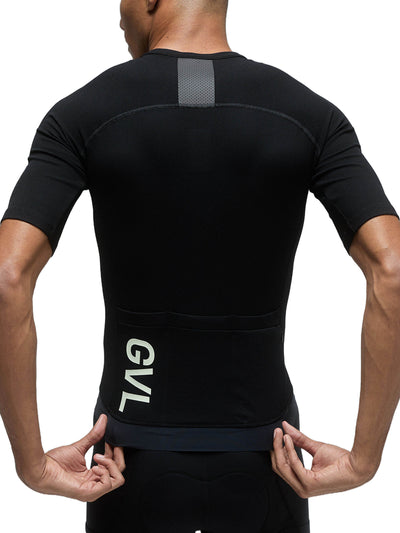 Rear view of a black Givelo Modern Classic jersey worn by a person, showcasing the jersey's sleek design with a reflective strip across the upper back for visibility and the 'GVL' branding on the lower back.