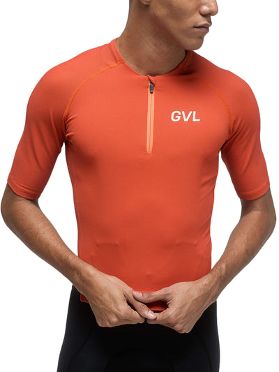Front view of a person wearing a pumpkin-colored Givelo Modern Classic jersey, emphasizing the half-zip closure, the waffle texture fabric, and the 'GVL' logo on the chest, blending functionality with a unique style.