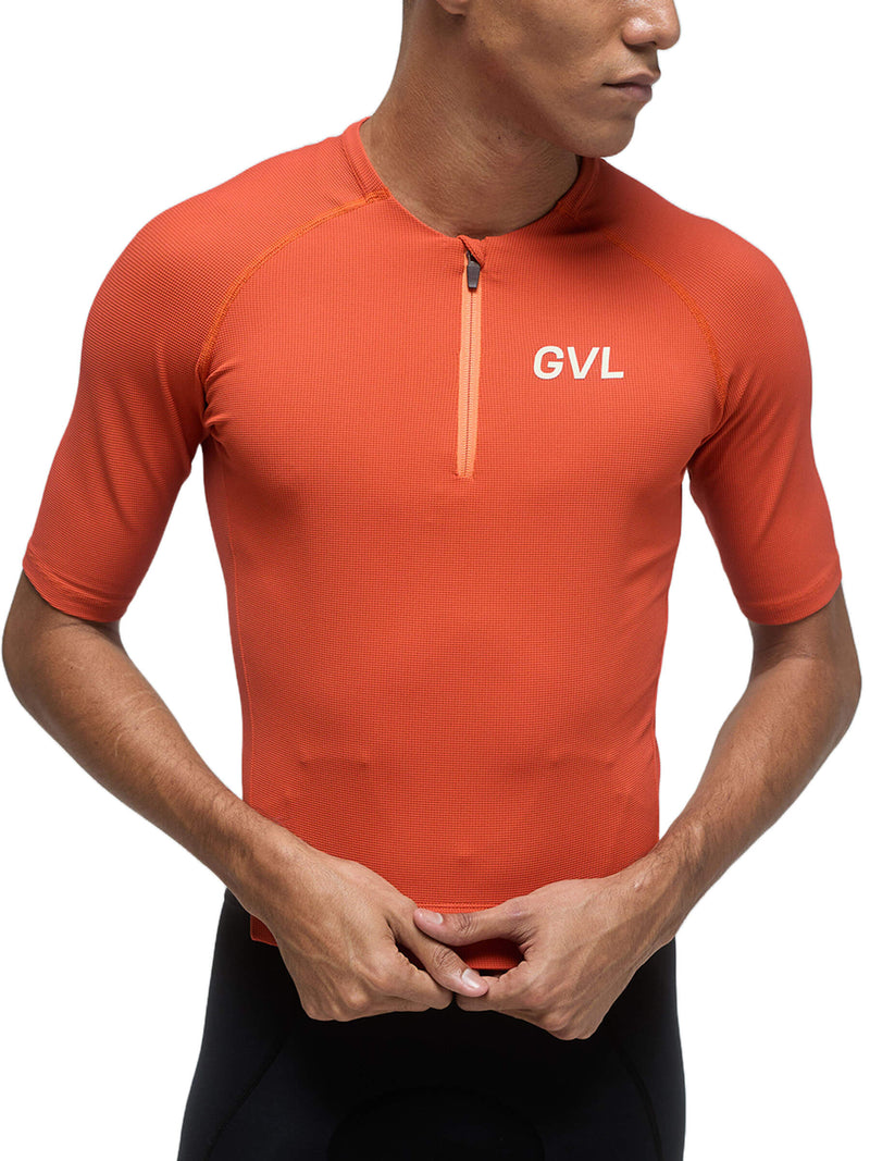 Front view of a person wearing a pumpkin-colored Givelo Modern Classic jersey, emphasizing the half-zip closure, the waffle texture fabric, and the &