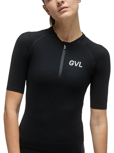 Front view of a woman wearing a black Givelo Modern Classic jersey, demonstrating the half-zip feature, snug fit, and the 'GVL' logo that represents the brand's commitment to breaking the norms of cycling apparel.
