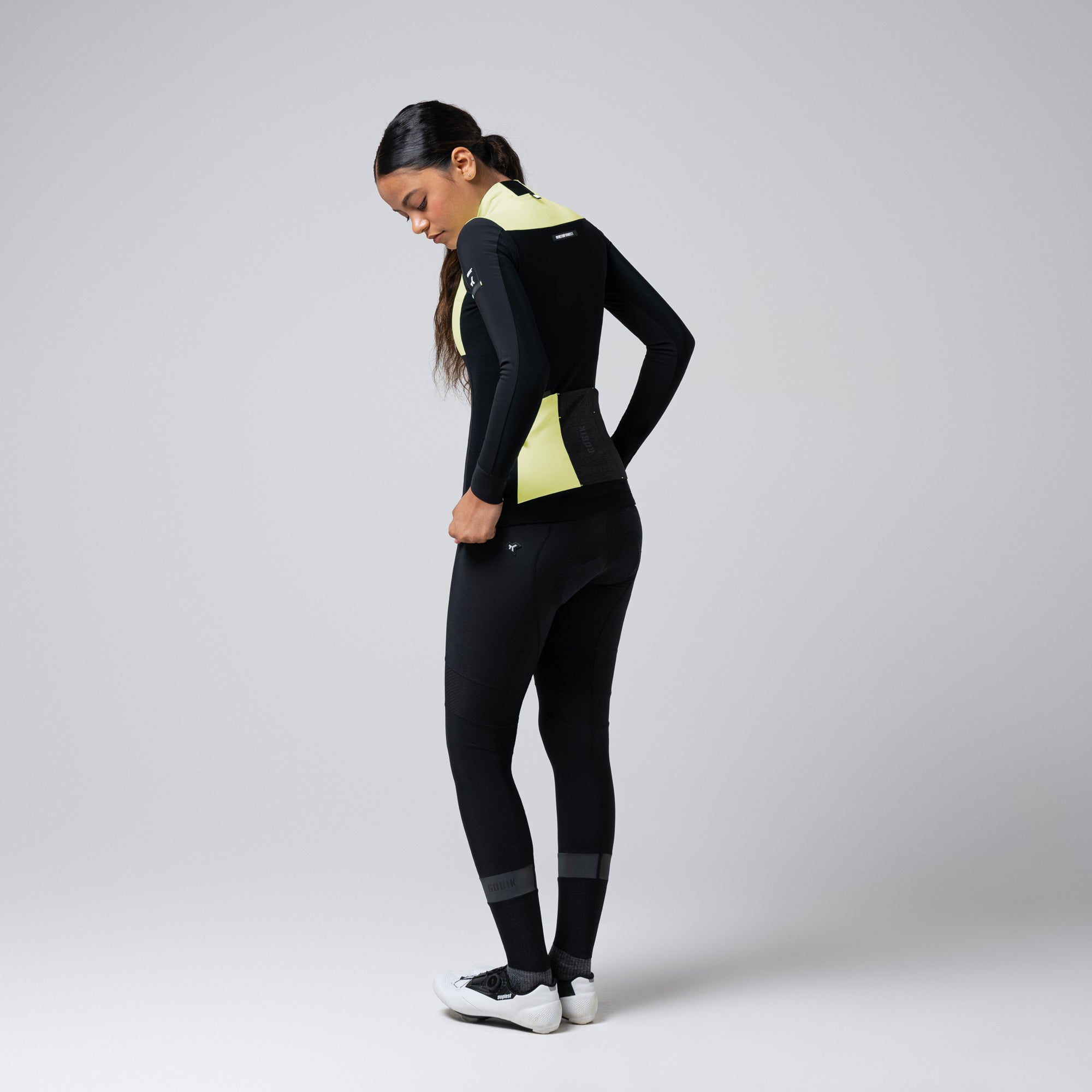 Woman wearing GOBIK Mist Blend 2.0 Jacket - Women's showing back view with black and yellow panels and reflective details