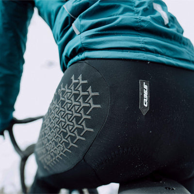 Cyclist wearing Q36.5 Grid Skin Winter Bib Tights showing rear protective design.