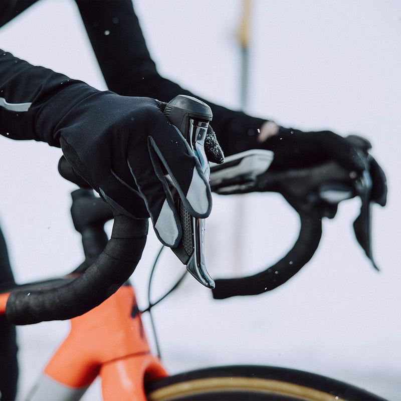 Close-up of black Q36.5 Hybrid Que X Gloves worn by a cyclist in action.