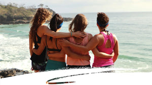 Four women alongside a coastline wearing Kinesys SPF 50+ unscented sunscreen