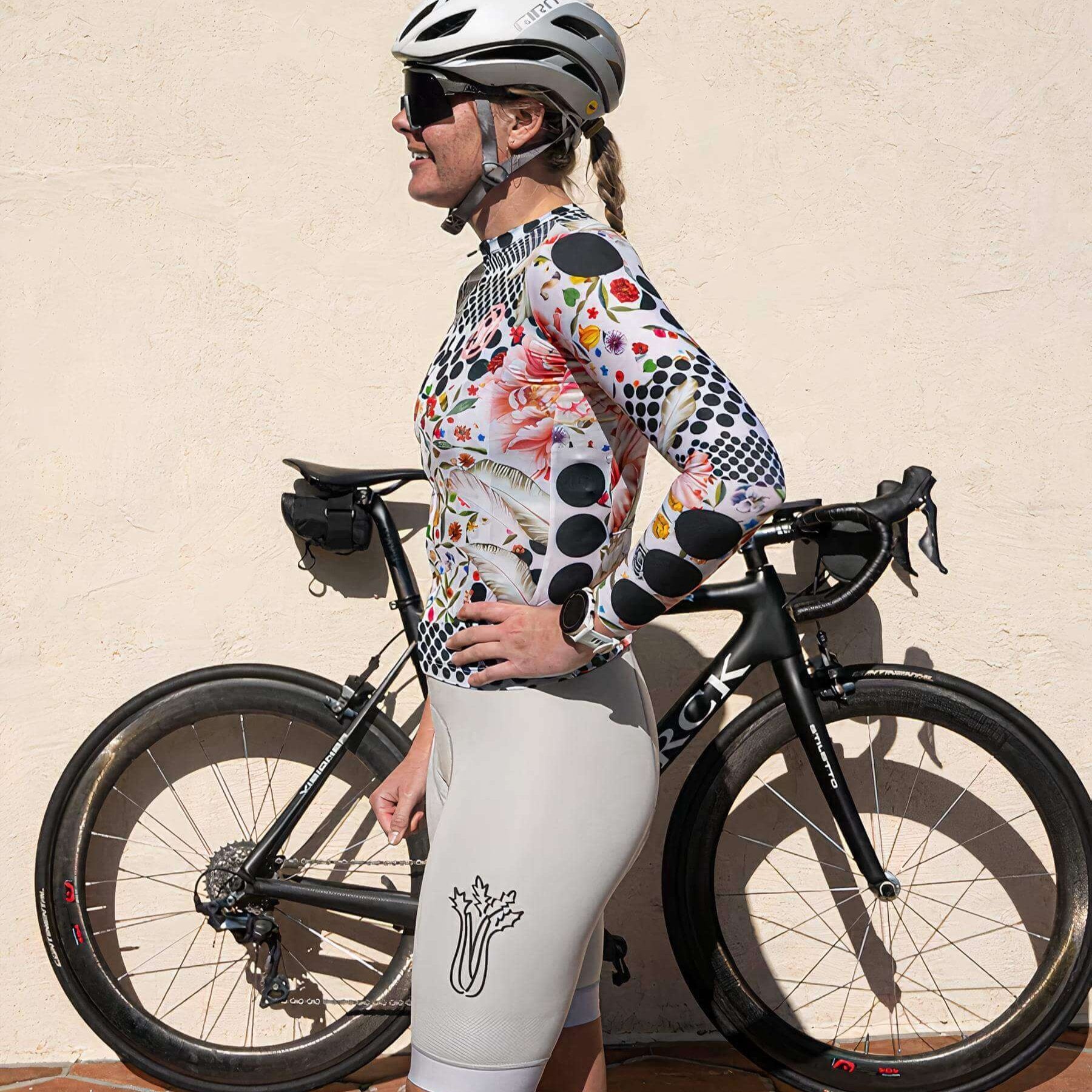 Woman wearing Ostroy Omloop White Lightweight Long-Sleeve Jersey - Women's standing next to black road bike in sunlight