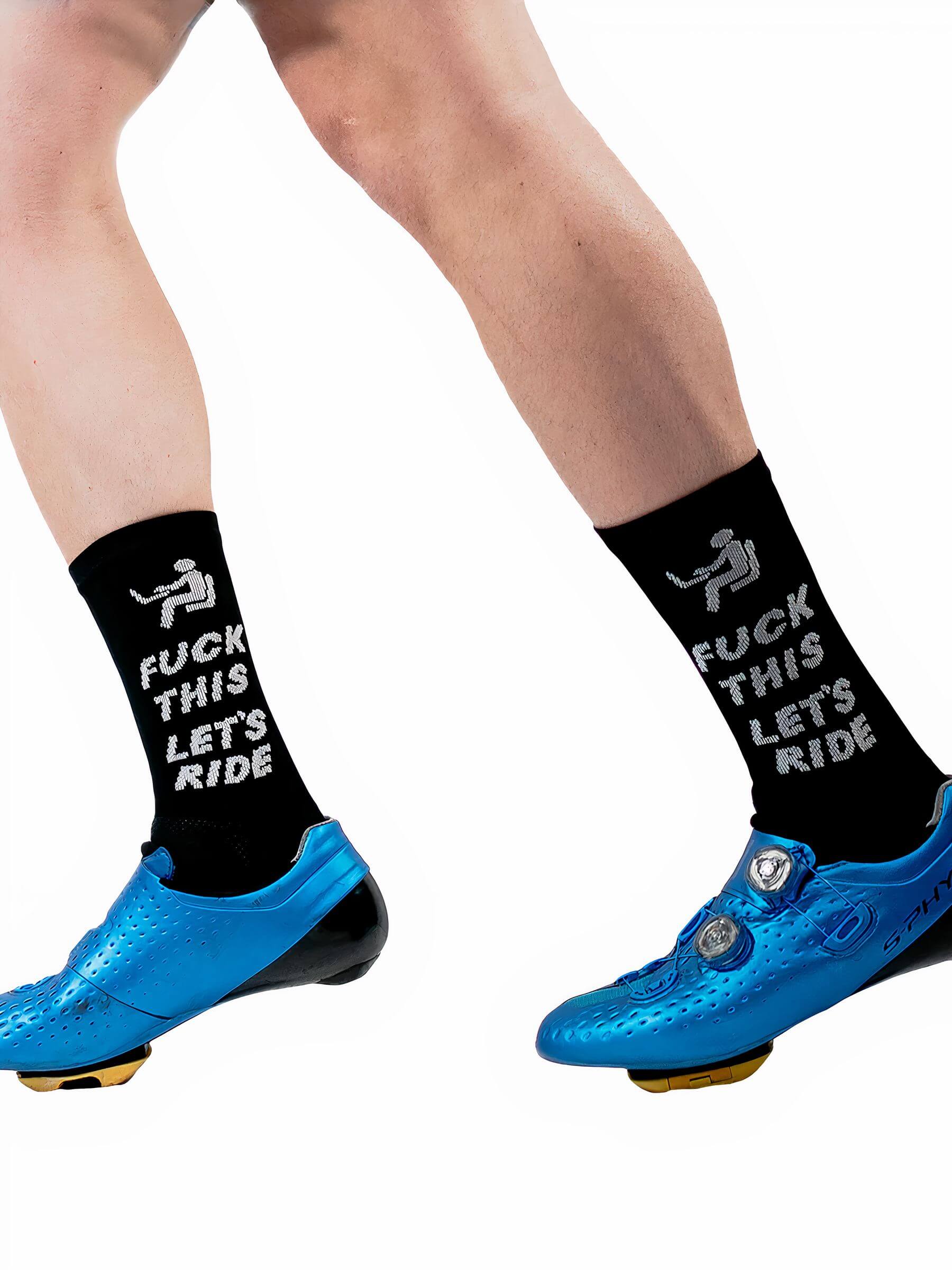 Legs wearing black Ostroy F This Let's Ride Socks with bold white text and blue cycling shoes against white background