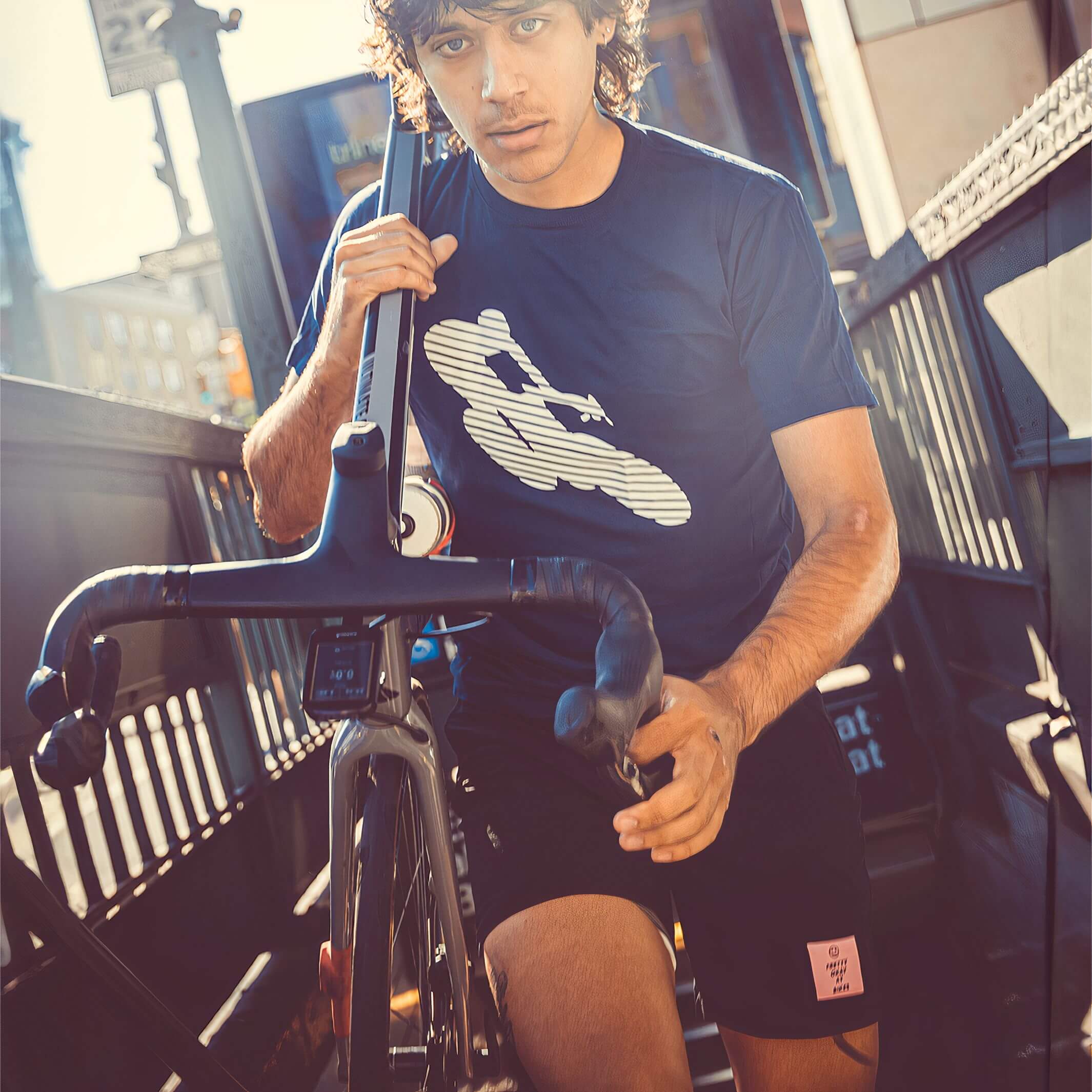 Man wearing Ostroy Bike Man T-Shirt - Unisex holding a road bike with reflective cyclist graphic on front outdoors