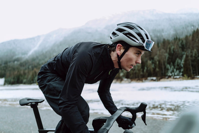 Action shot of a cyclist in the black Q36.5 Bat Shell Long Sleeve Jersey, showcasing its practicality and performance in wet and cold conditions.