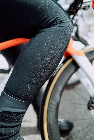 A cyclist in motion wearing Q36.5 Winter Bib Tights, illustrating the ergonomic fit and comfort during a snowy mountain ride.