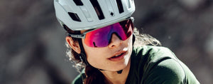 women wearing the sweet protection MIPS outrider helmet in matte white with the shinobi RIG reflect in bixbite with nardo grey