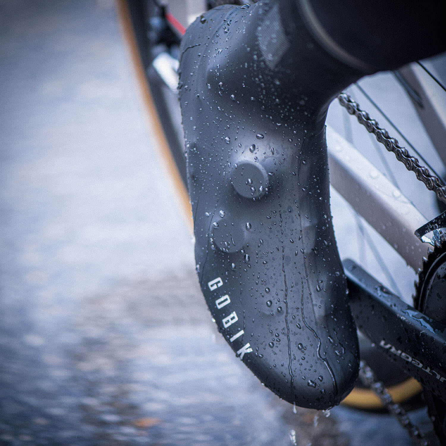 GOBIK VELOTOZE Snaps Tall Overshoes - Unisex in black with water droplets showcasing water resistance on bicycle pedal area