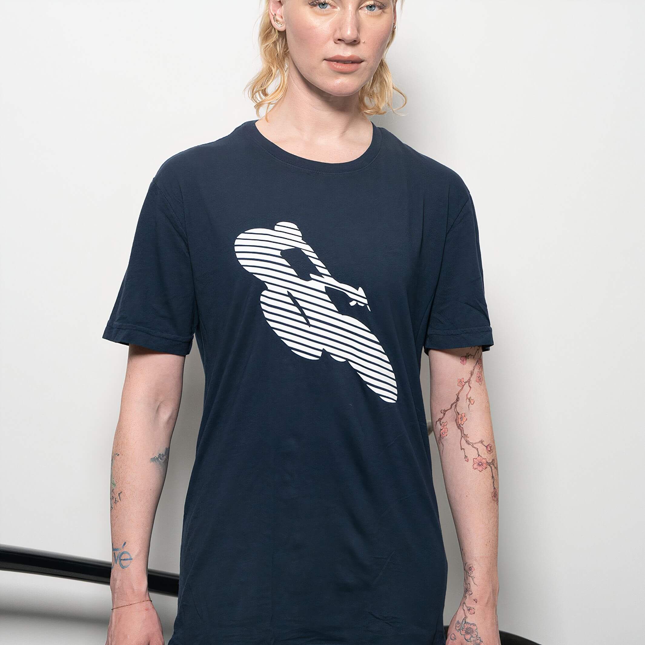 Woman wearing Ostroy Bike Man T-Shirt - Unisex in navy with white graphic cyclist design on front against plain background