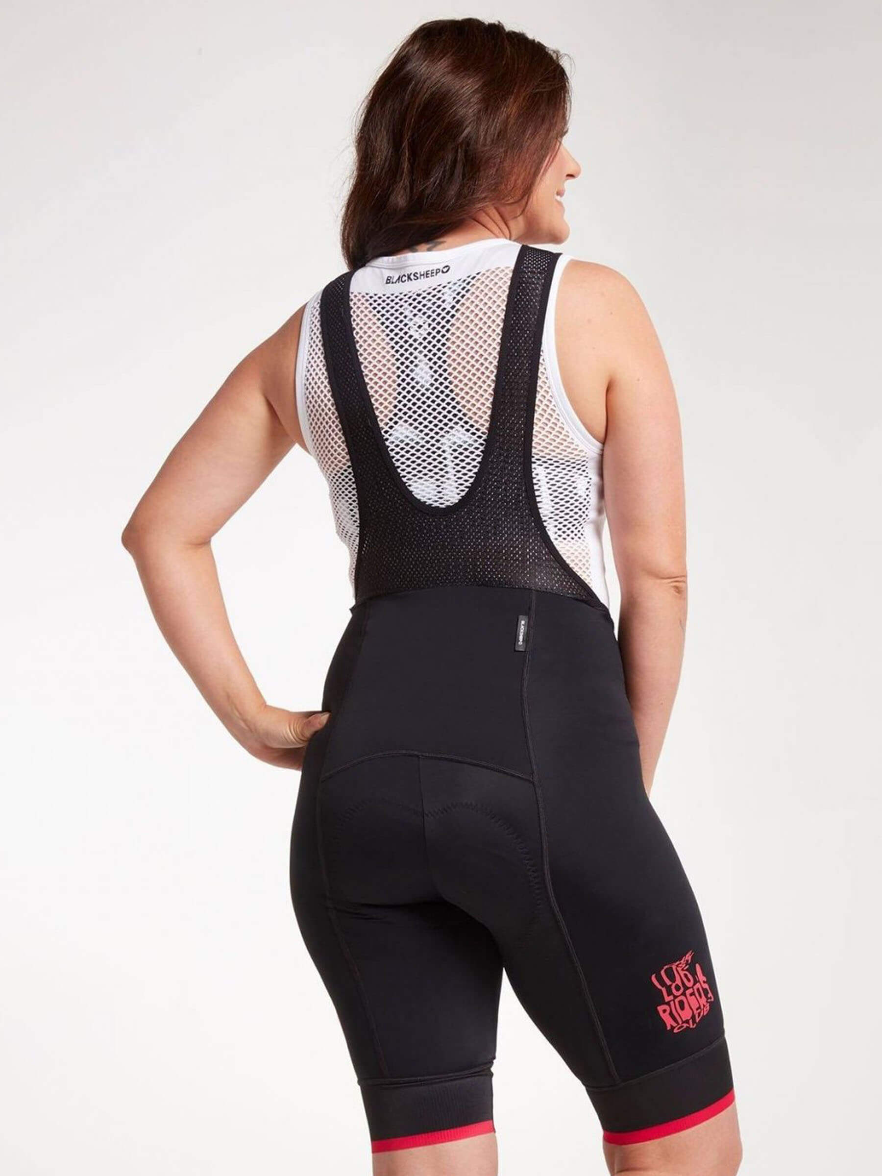 Woman wearing Black Sheep Cycling women's bib shorts in black and pink. Durable and comfortable with CorePower compression fabric.