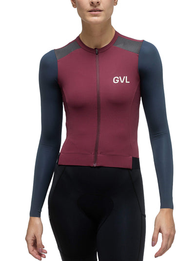 A full front view of a female model wearing the Givelo Modern Classic long sleeve jersey in burgundy with grey and navy panels, zipped up and fitted, showing the torso and sleeve details.