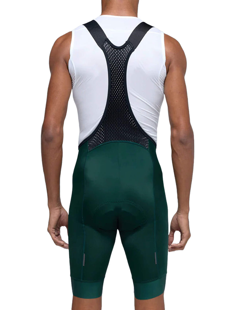The rear view of a man wearing Givelo Classic Bib Shorts. The design features a white upper section with a ventilated back panel and contrasting black straps that form a Y-shape. The shorts extend to mid-thigh, with a snug fit and dark green color. The design includes subtle reflective details and padding in key areas for added comfort during long rides.