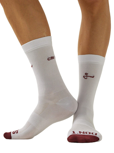 Image showing a front view of a pair of feet wearing Givelo G-Socks in white with red accents. The socks have distinct cushioning on the sole and a ribbed texture for grip, along with the brand's logo on the cuff and footbed.