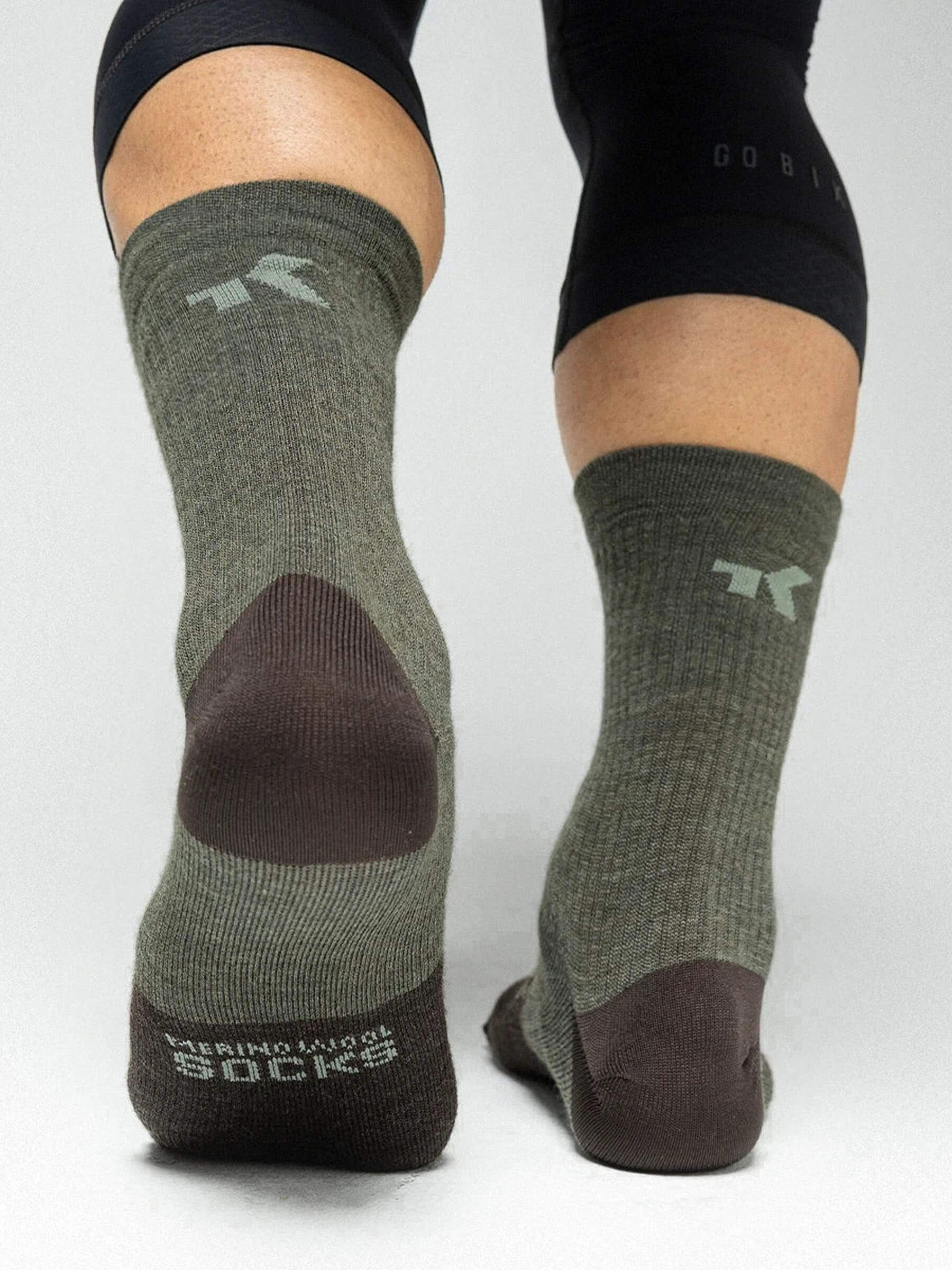 Rear view of feet wearing GOBIK Winter Merino Socks in olive green and brown, designed for warmth and comfort in cold weather.