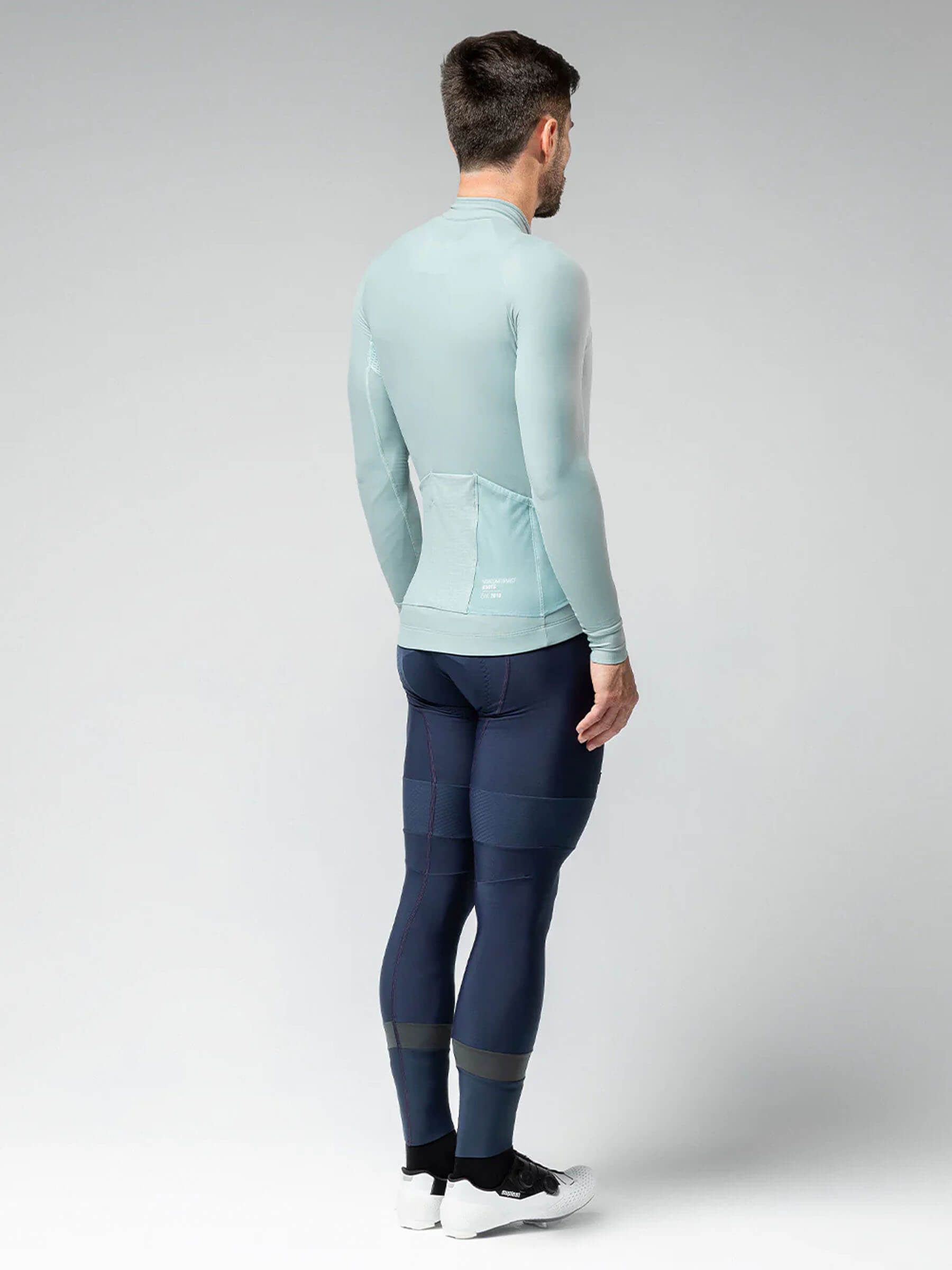 Male model wearing GOBIK Pacer Solid Long Sleeve Jersey - Men's in light blue shown from the back with cycling pants