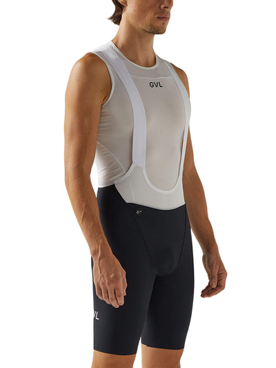 Front view of a man in black Givelo HD Pro Bib Shorts featuring a white "GVL" logo on the thigh. The shorts are engineered for high-density support and comfort, suitable for extensive cycling ventures.