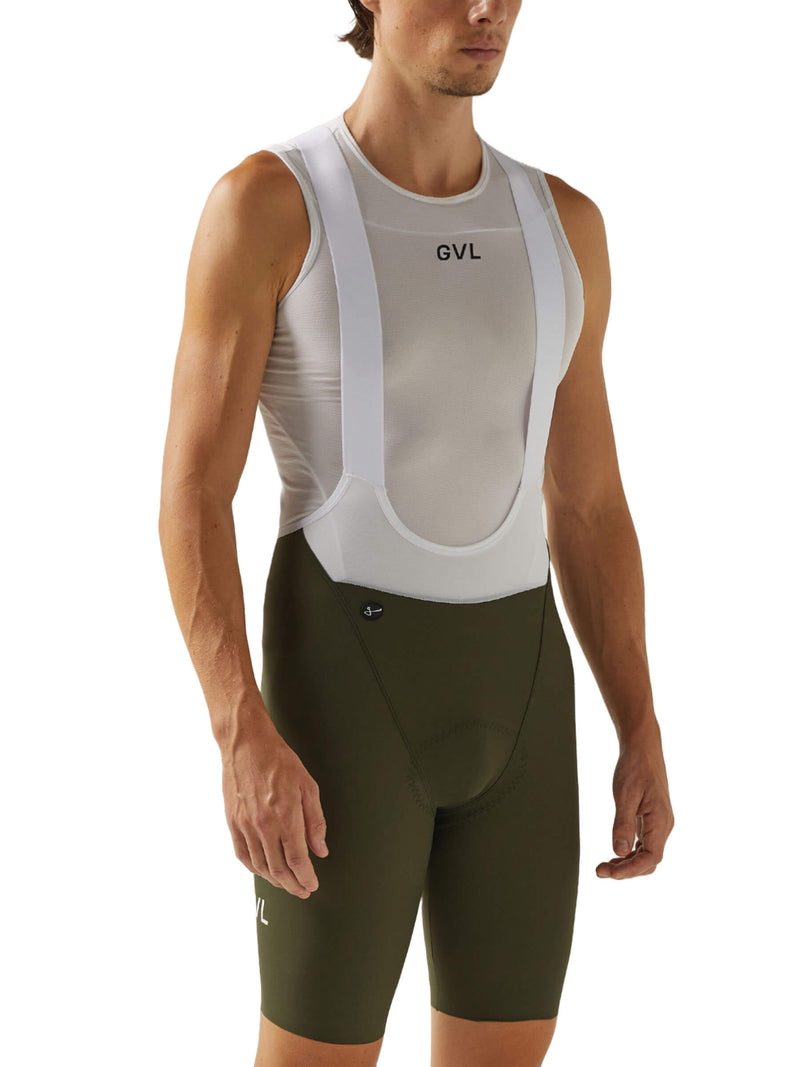Front view of a man in black Givelo HD Pro Bib Shorts featuring a white "GVL" logo on the thigh. The shorts are engineered for high-density support and comfort, suitable for extensive cycling ventures.