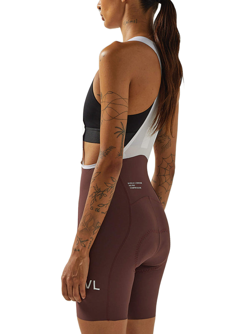 Side view of a woman in wine-colored Givelo HD Pro Bib Shorts, demonstrating the snug fit and the "GVL" logo on the thigh, indicating the shorts&