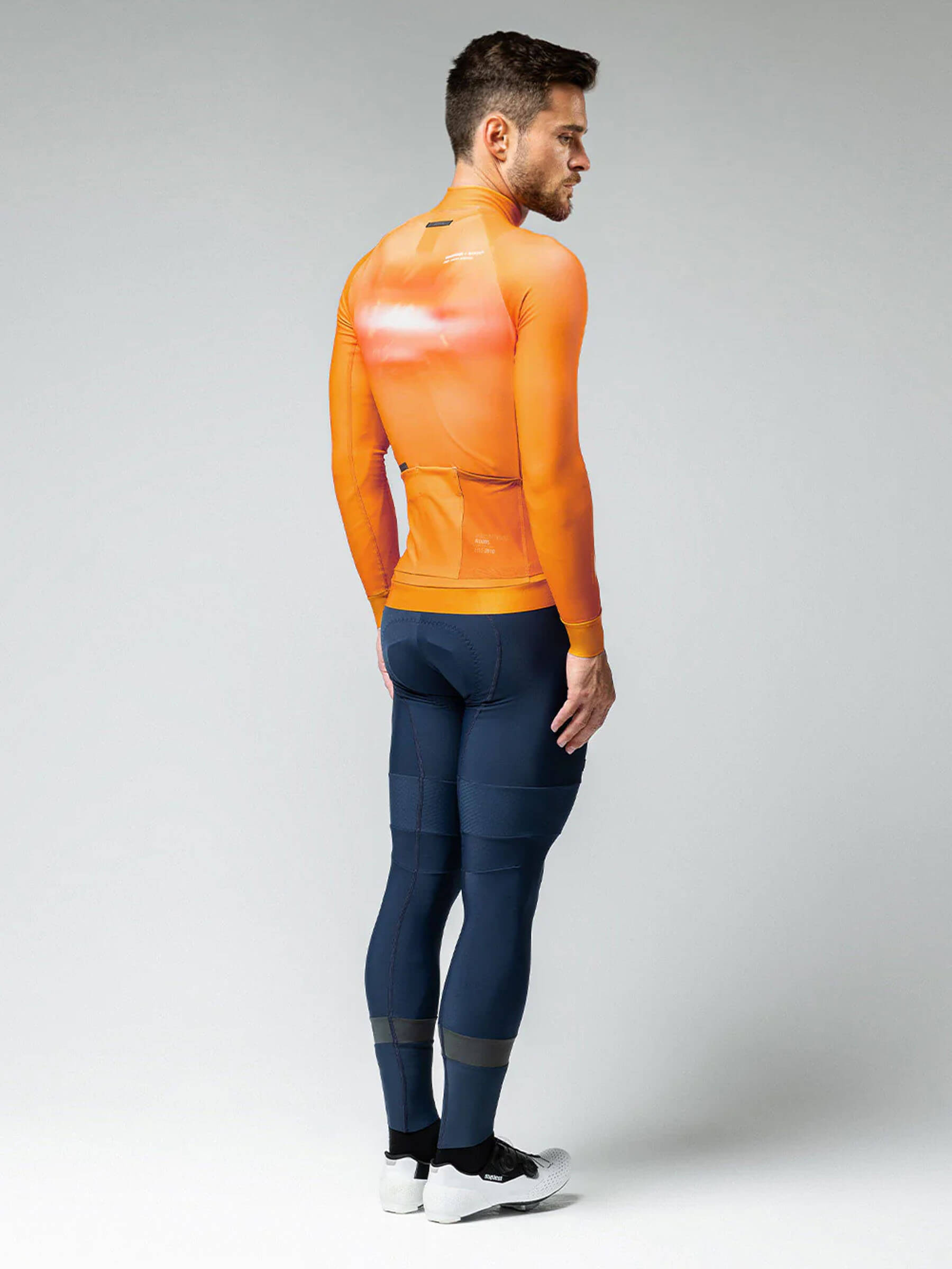 Rear view of a man in a cheddar-colored GOBIK Hyder jersey, with back pockets and side mesh for essentials.