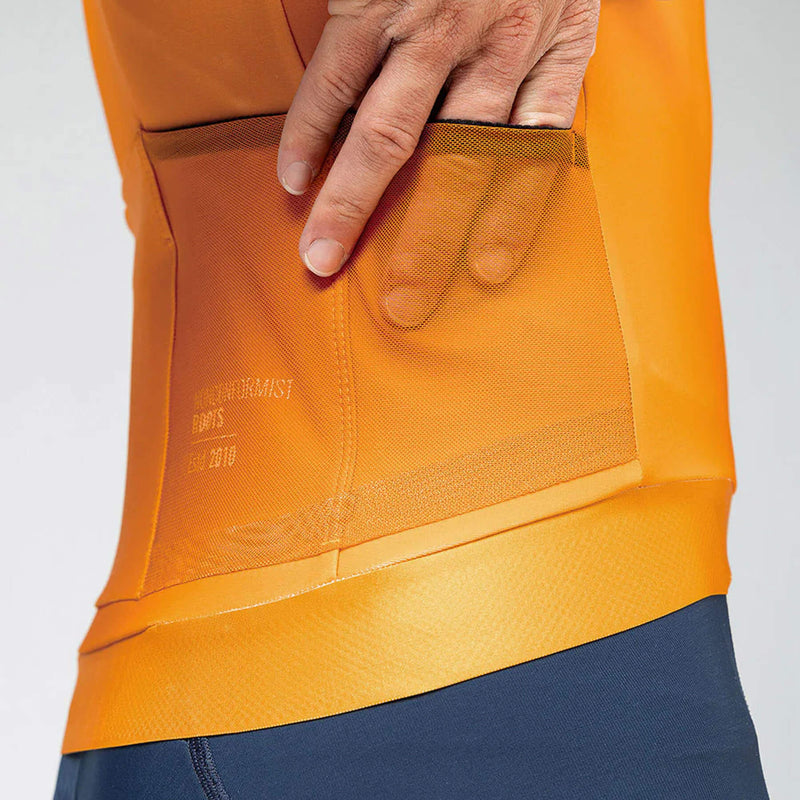 Rear view of a man in a cheddar-colored GOBIK Hyder jersey, with back pockets and side mesh for essentials.