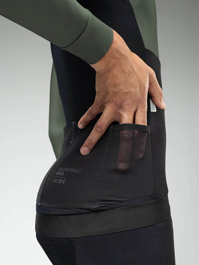 Detail of cyclist reaching into the back pocket of the Hyder Blend Jersey, highlighting the smart pocket system and secure fit.