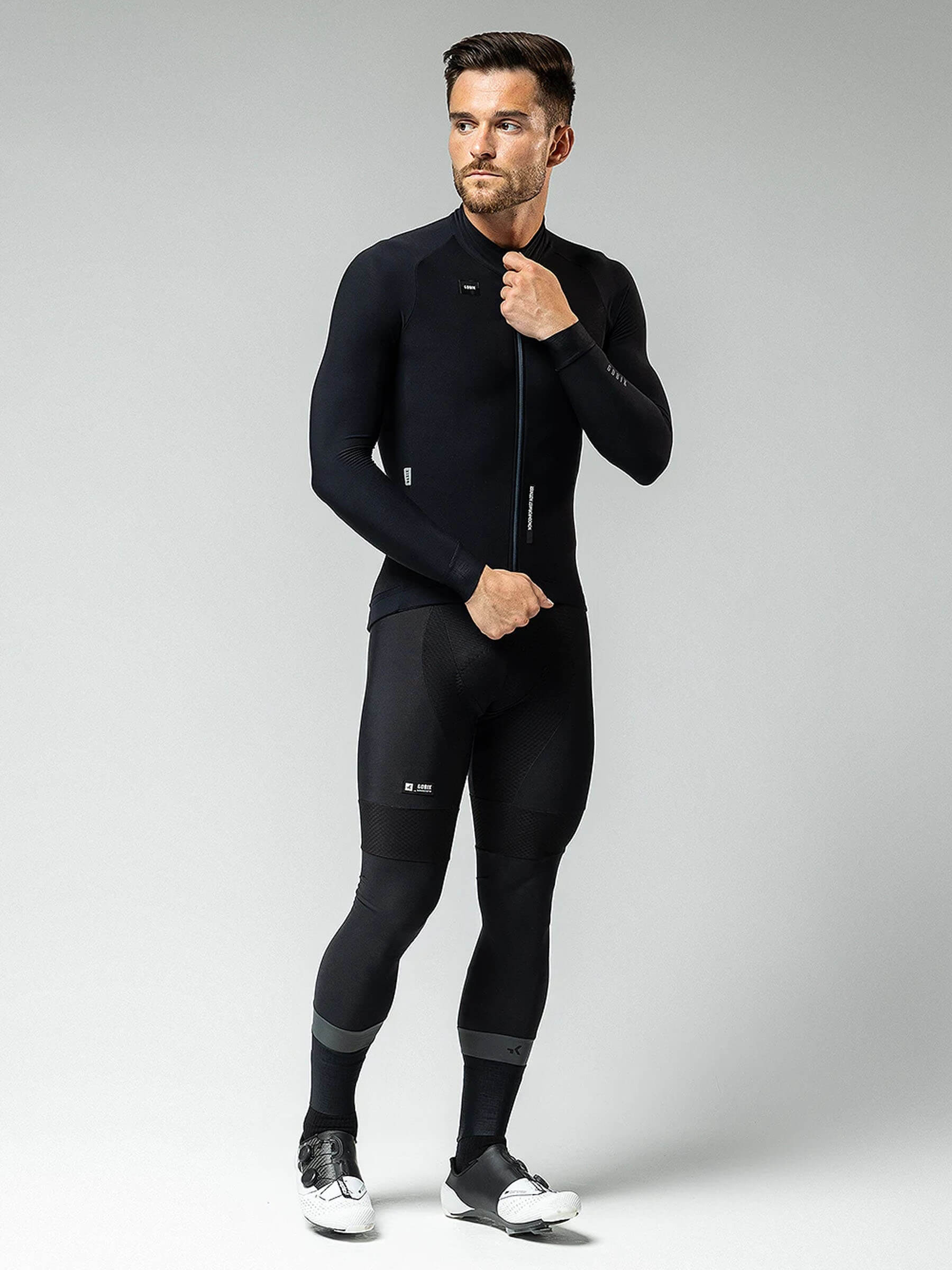 Male model wearing black GOBIK Pacer Solid Long Sleeve Jersey - Men's cycling apparel in studio setting