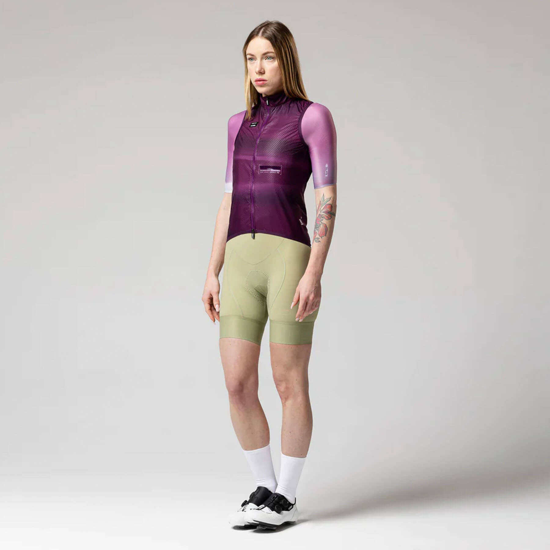 Woman wearing GOBIK Vest Plus 2.0 - Women's in purple with cycling shorts standing against plain background