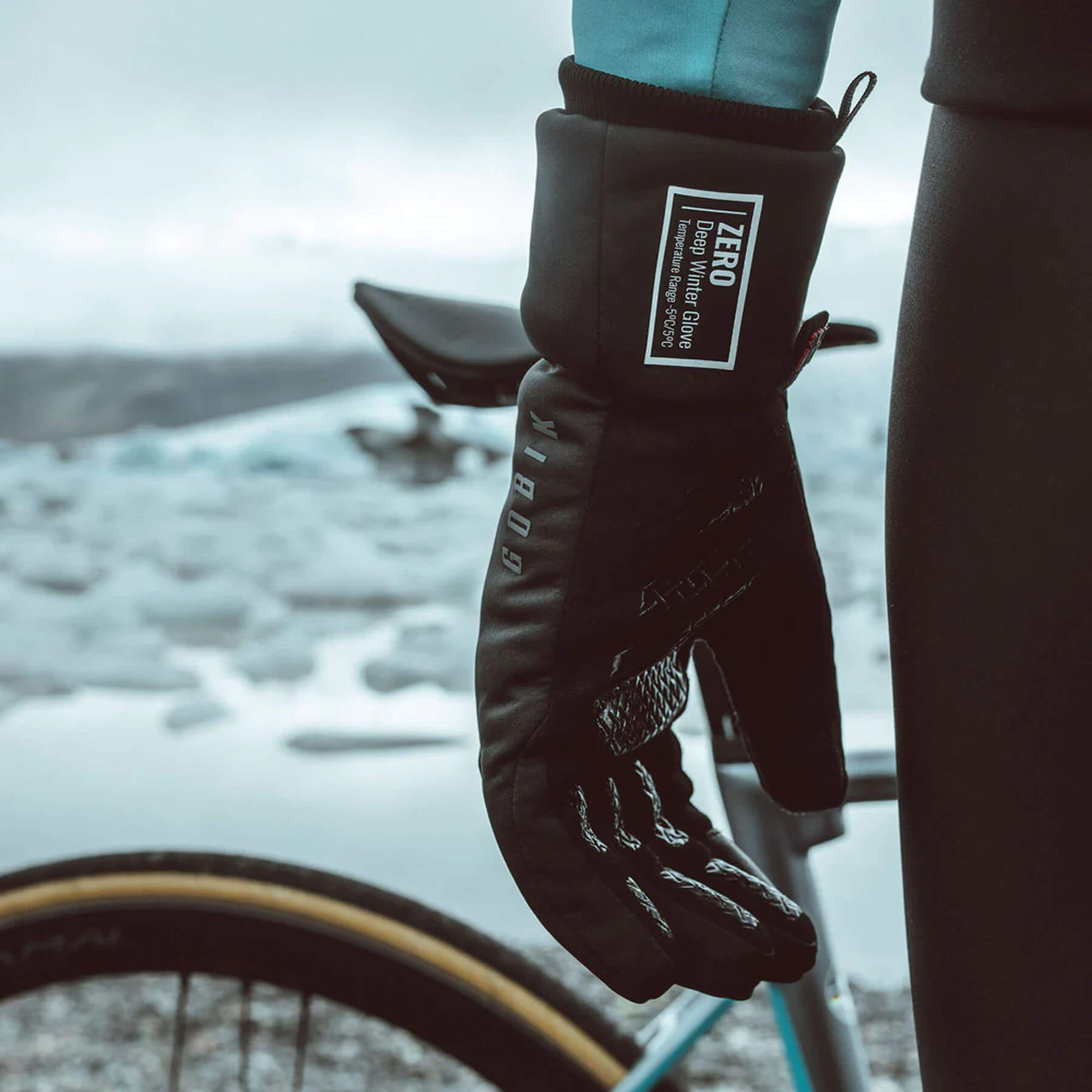 Close-up of cyclist wearing GOBIK Zero Primaloft Winter Gloves - Unisex with thermal insulation near snowy landscape