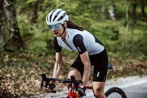 a women riding a road bike wearing Q36.5 clima short sleeve jersey in white with black bib shorts, roadkit