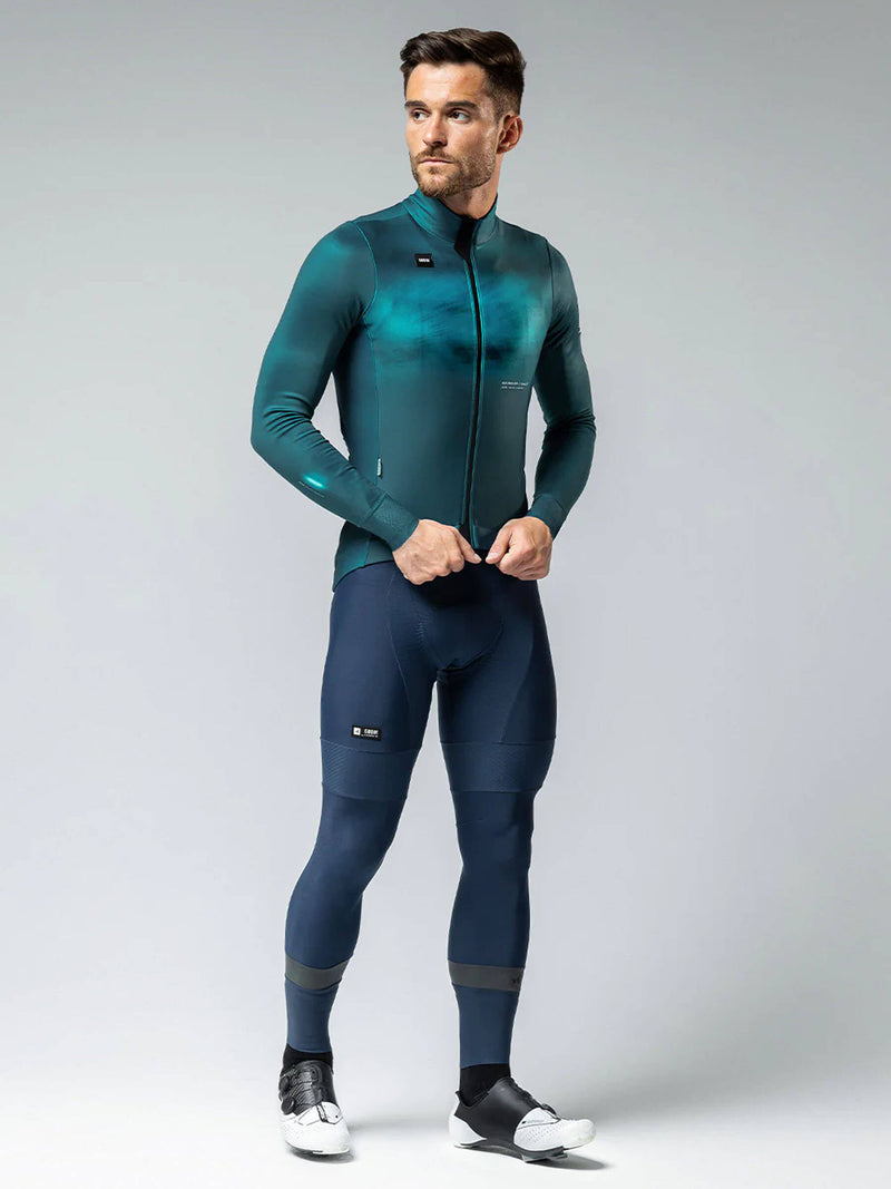 Full-length view of a man in GOBIK Skimo Pro Hydro full kit in teal and navy, suitable for cold season rides from 0 to 12C.