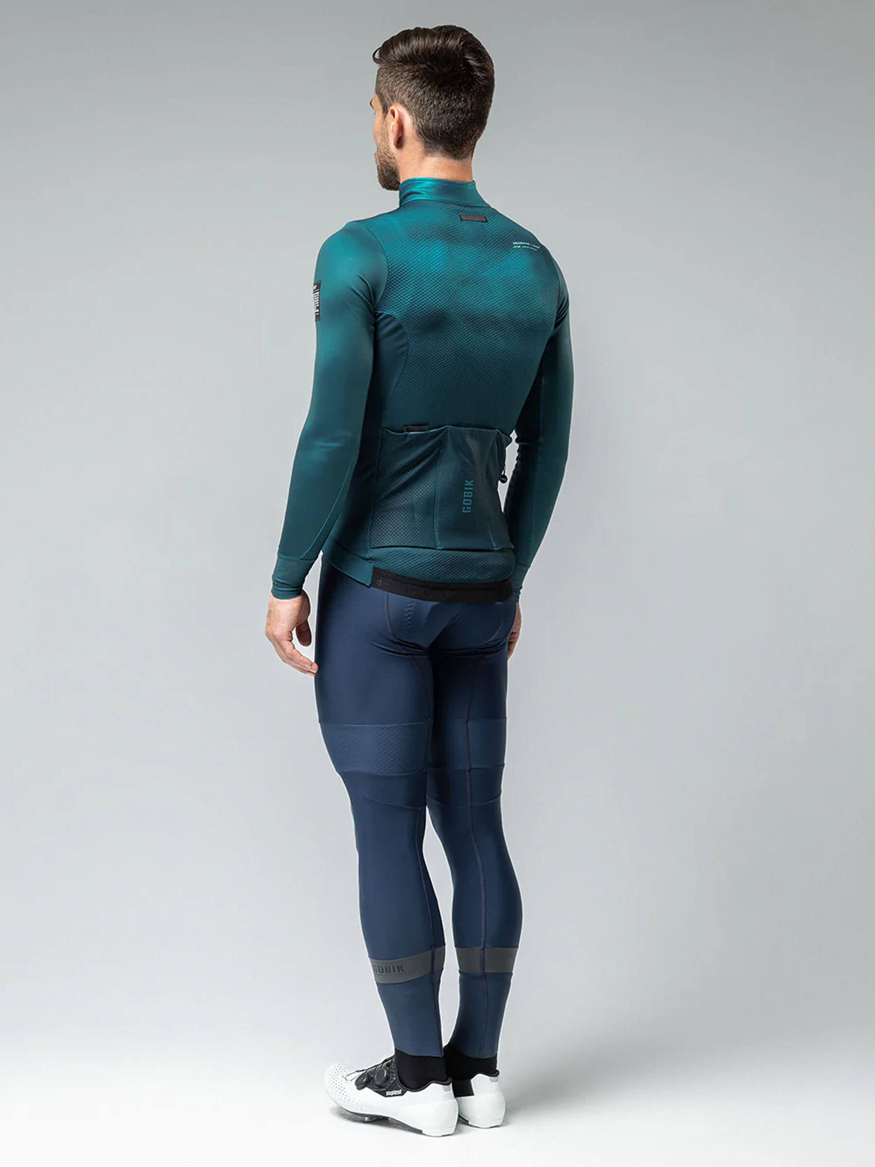 Full-length view of a man in GOBIK Skimo Pro Hydro full kit in teal and navy, suitable for cold season rides from 0 to 12C.