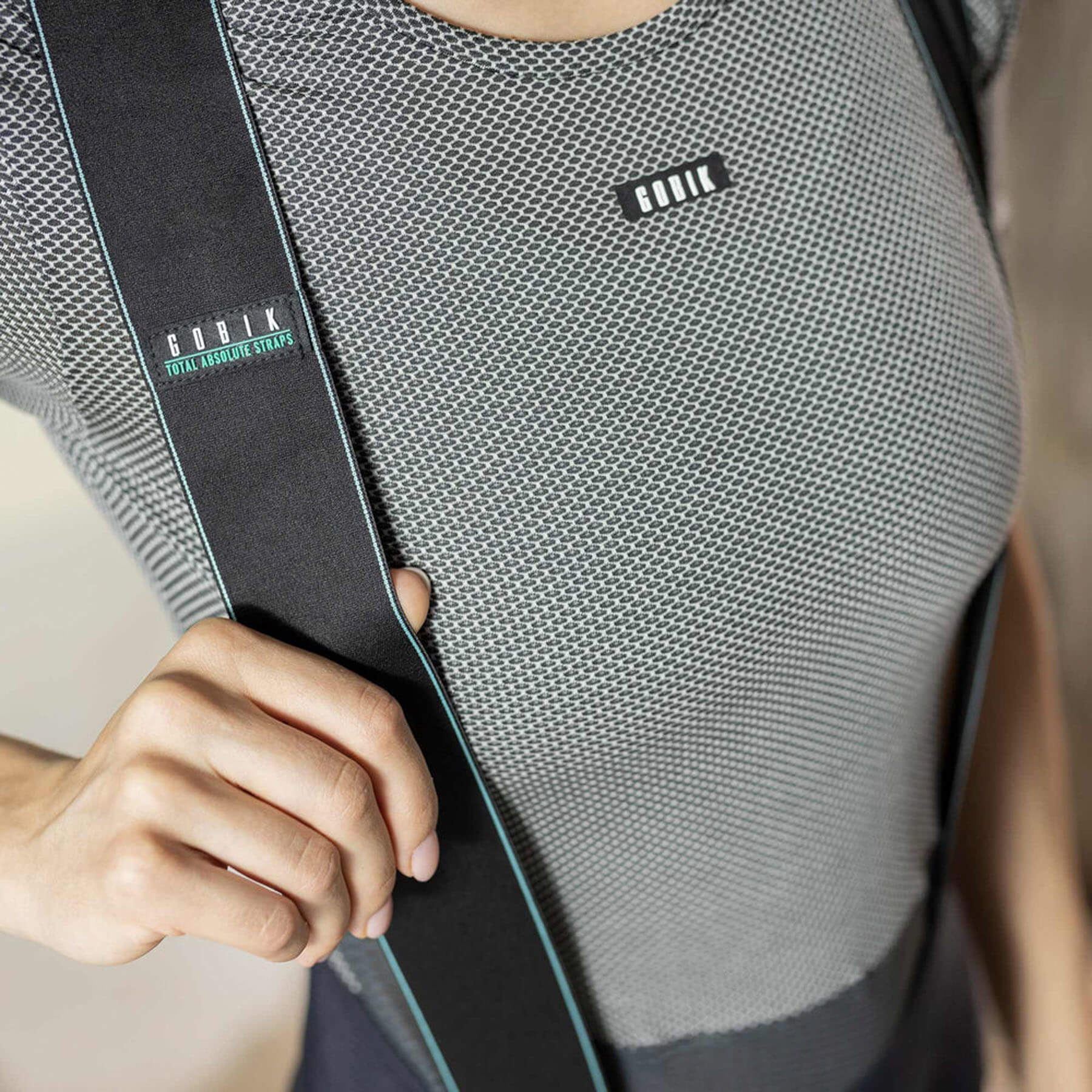 Close-up of the GOBIK base layer worn by a woman, focusing on the upper chest area with the brand logo and the mesh fabric's hexagonal texture for breathability.