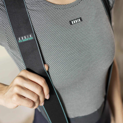 Close-up of the GOBIK base layer worn by a woman, focusing on the upper chest area with the brand logo and the mesh fabric's hexagonal texture for breathability.
