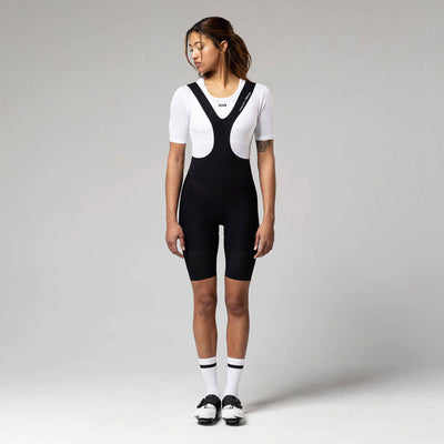 A woman in a contemplative pose wearing the GOBIK women's short-sleeved base layer, showing the snug fit and mesh ventilation zones for cooling.