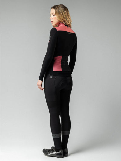 A woman in a pink and black cycling jersey, featuring the Women's Jacket: MIST BLEND 2.0, designed for peak performance and protection.