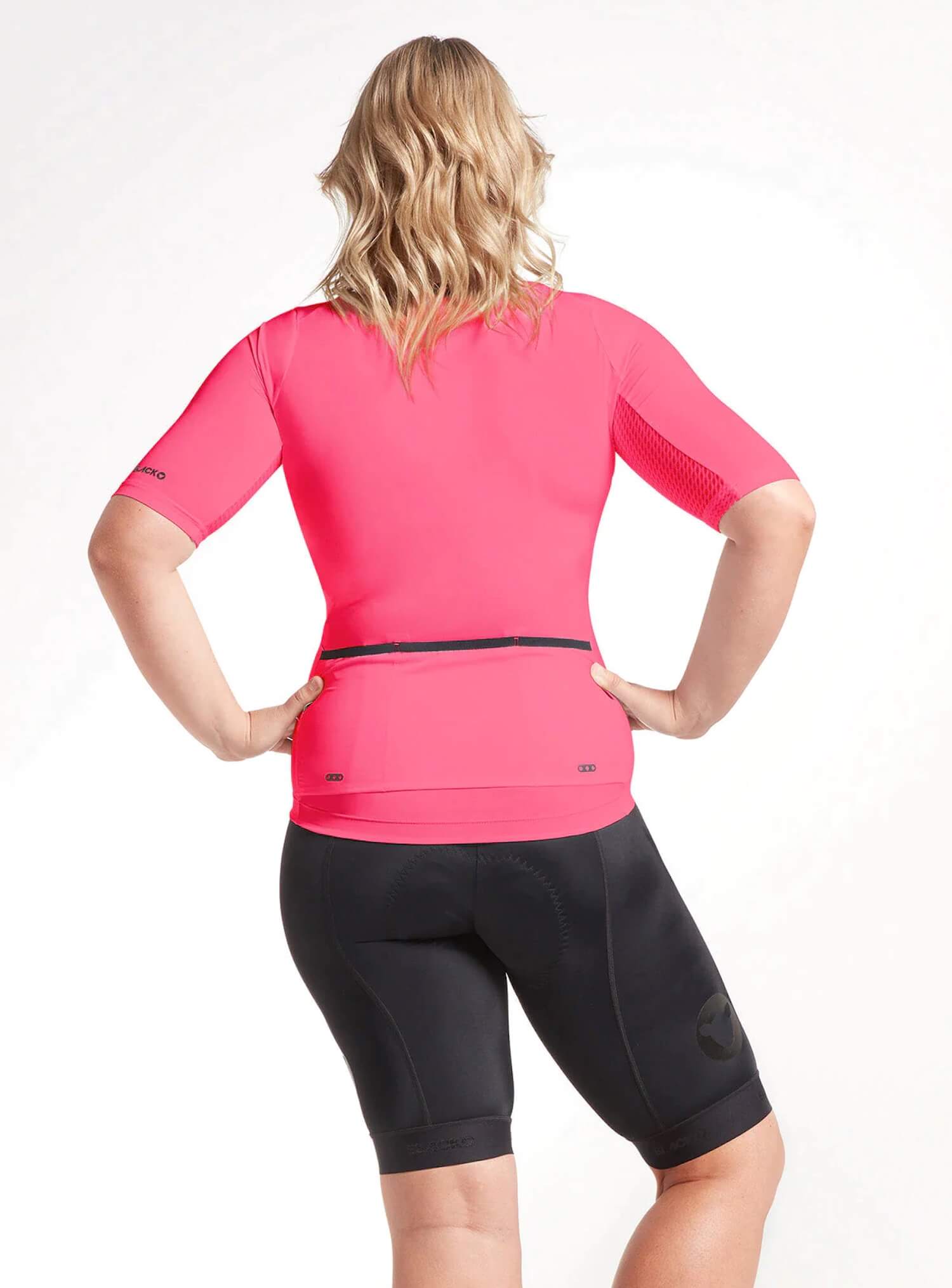 Woman wearing Black Sheep Cycling Essentials TEAM Jersey SS22- Women's in bright pink, shown from the back with cycling shorts