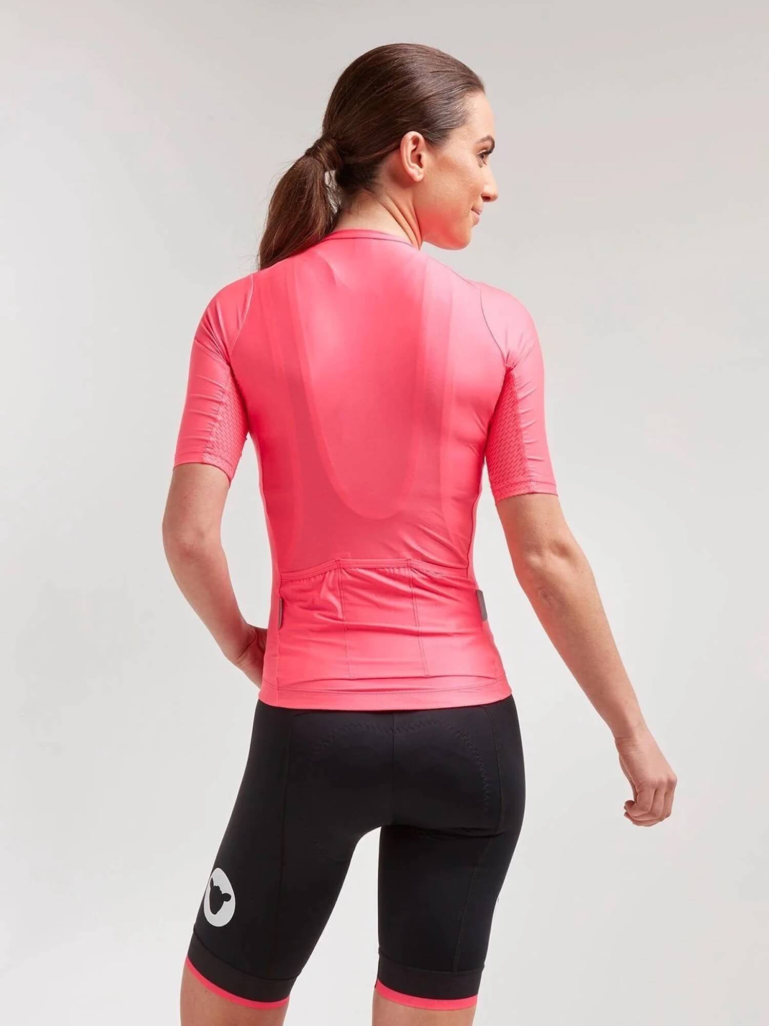 Woman seen from behind wearing Black Sheep Cycling Essentials TEAM Jersey - Women's in vibrant pink with black cycling shorts