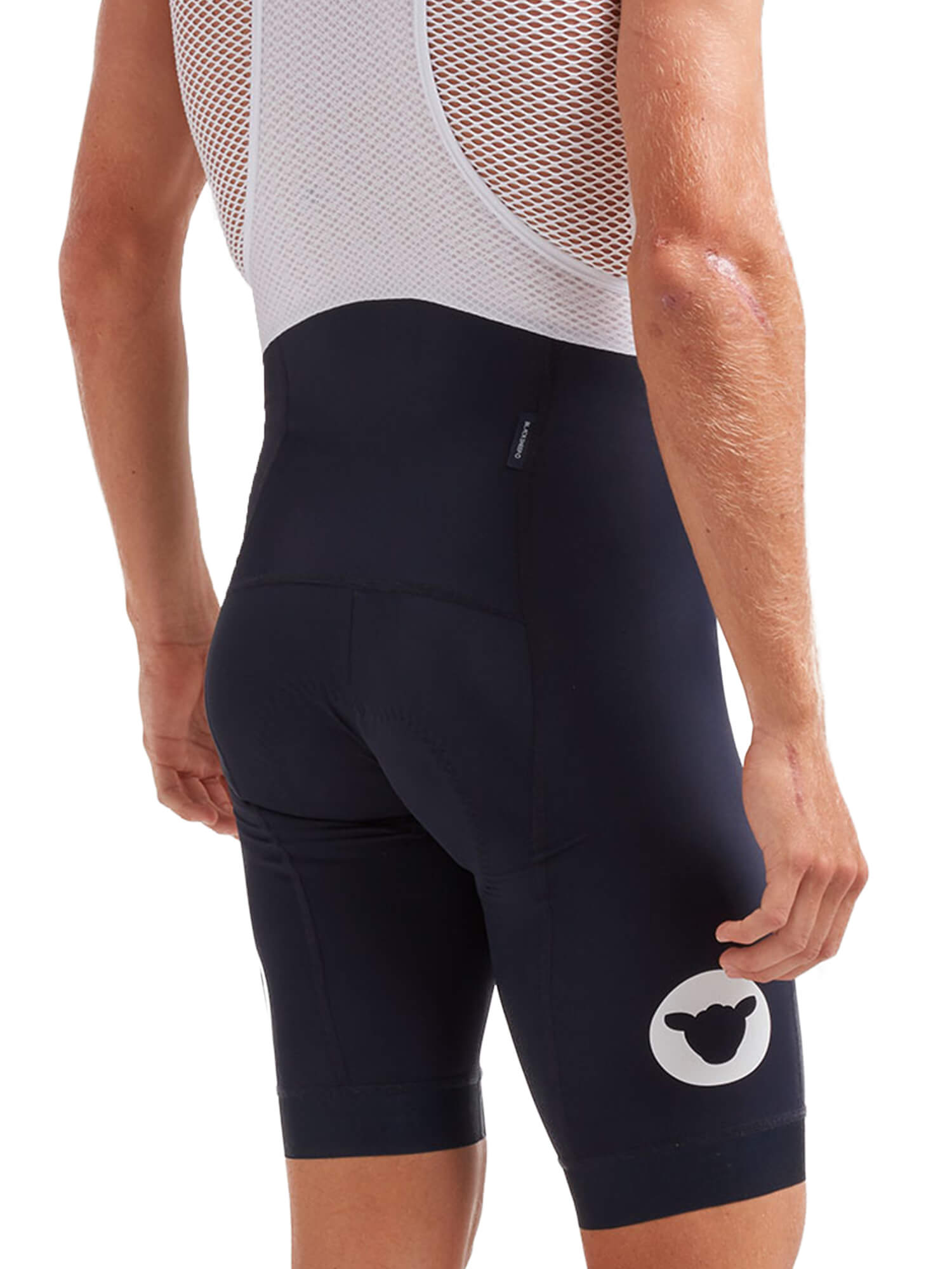 Rear view of a man wearing Black Sheep Cycling Essentials TEAM Bib - Men's with mesh upper and logo on leg