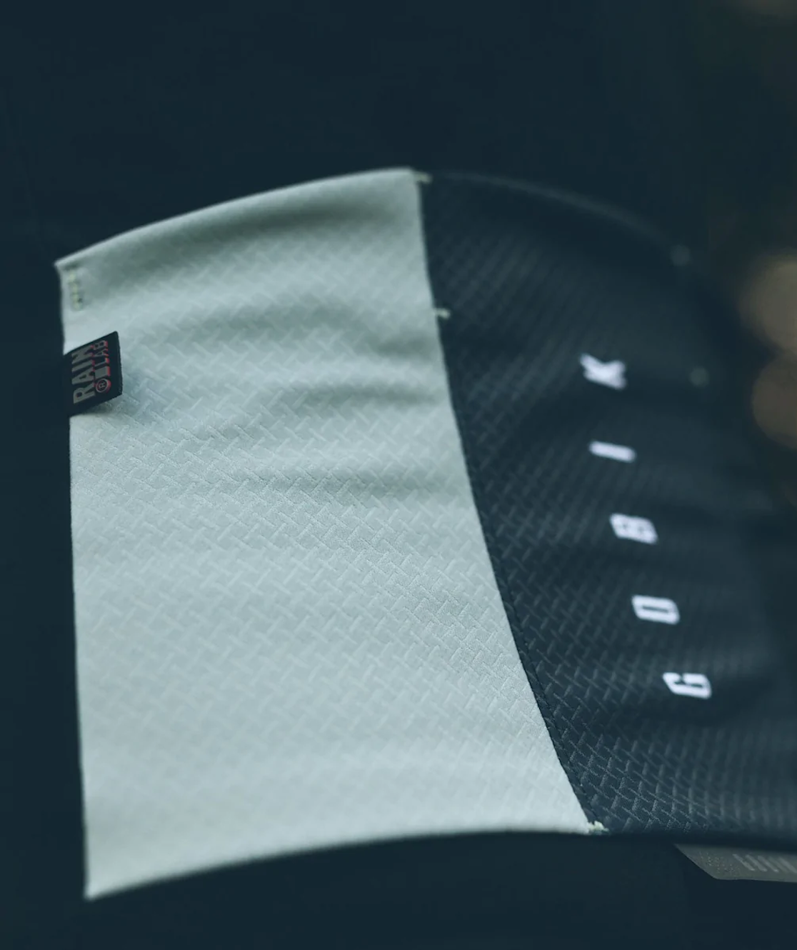 Close-up of GOBIK Mist Jacket - Women's fabric texture showing laminated surface with black and light grey panels