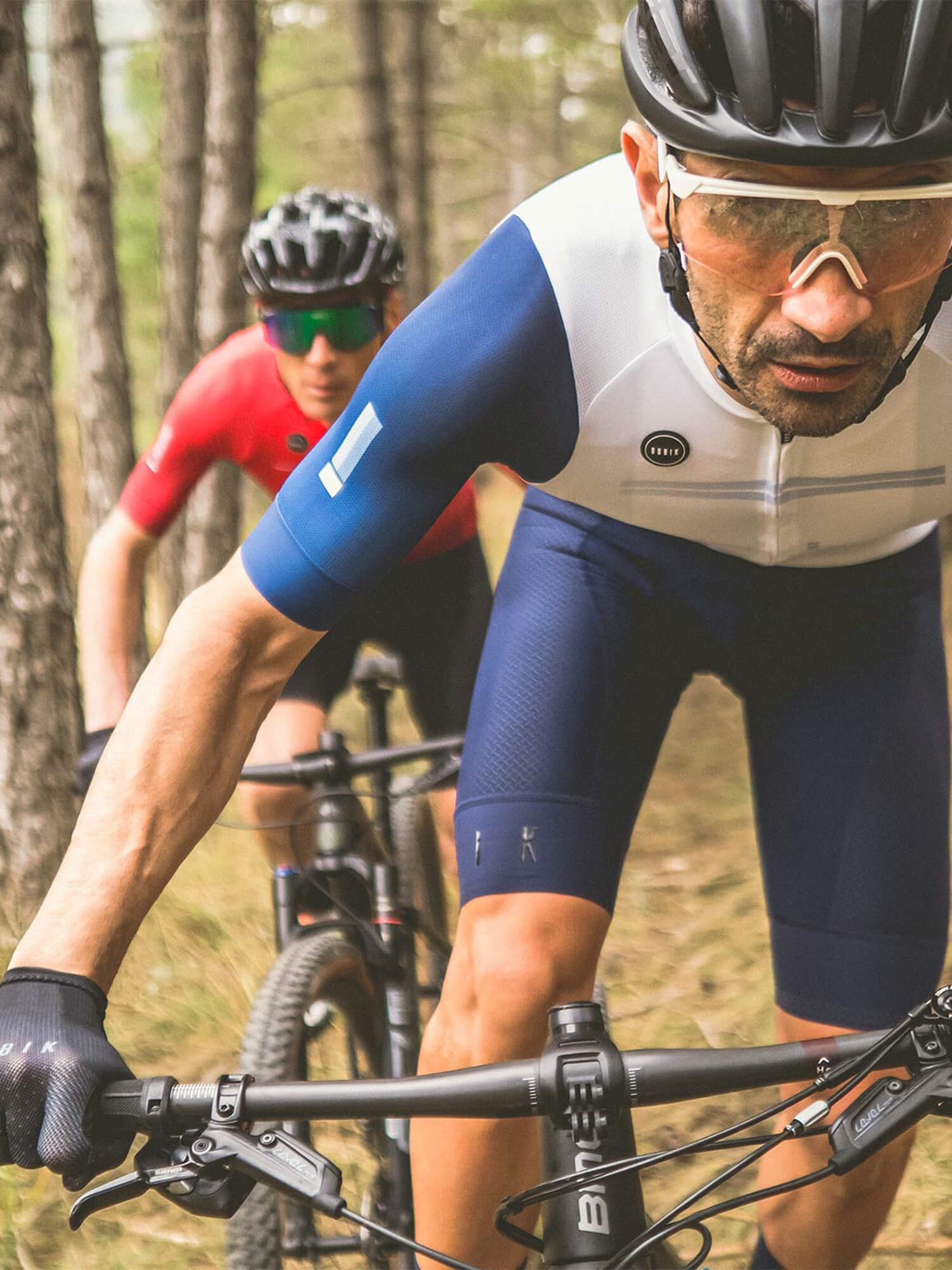 Cyclist wearing GOBIK CX Pro Unisex Short Sleeve Jersey - SS21 riding mountain bike in forest trail close-up